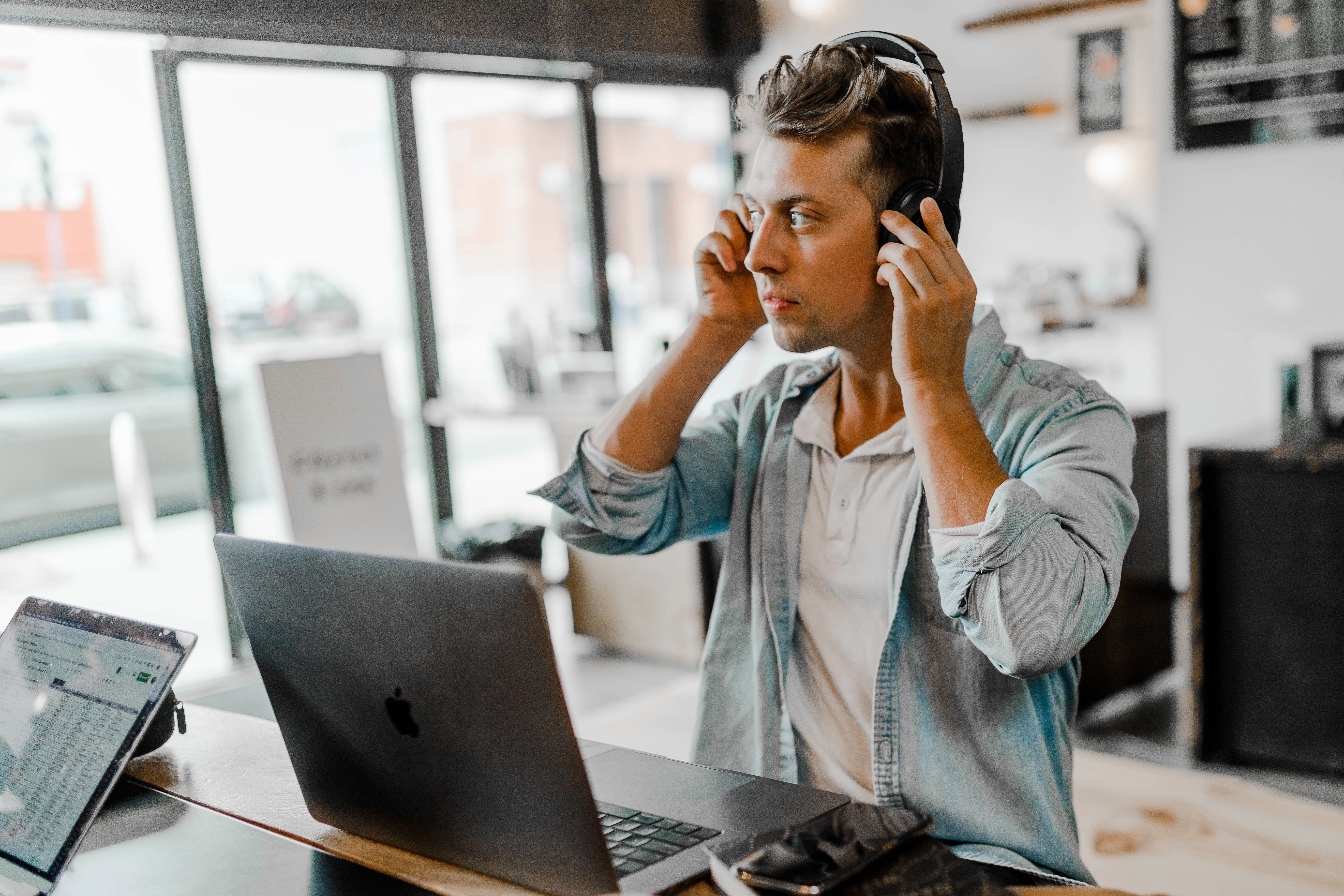 Um homem em pé colocando um fone de ouvido na frente de um computador na mesa