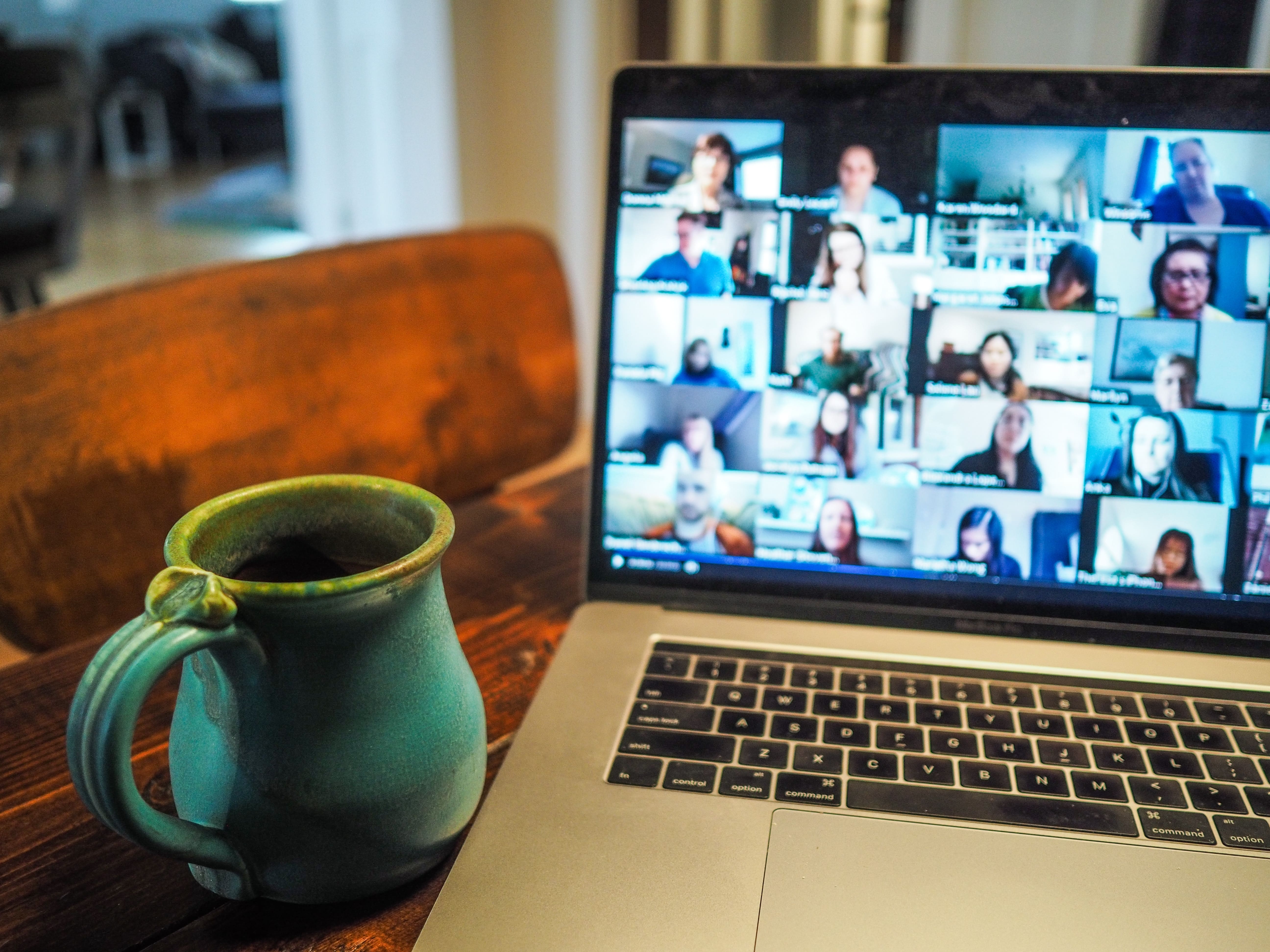 Computador ligado em uma videconferência com uma caneca ao lado