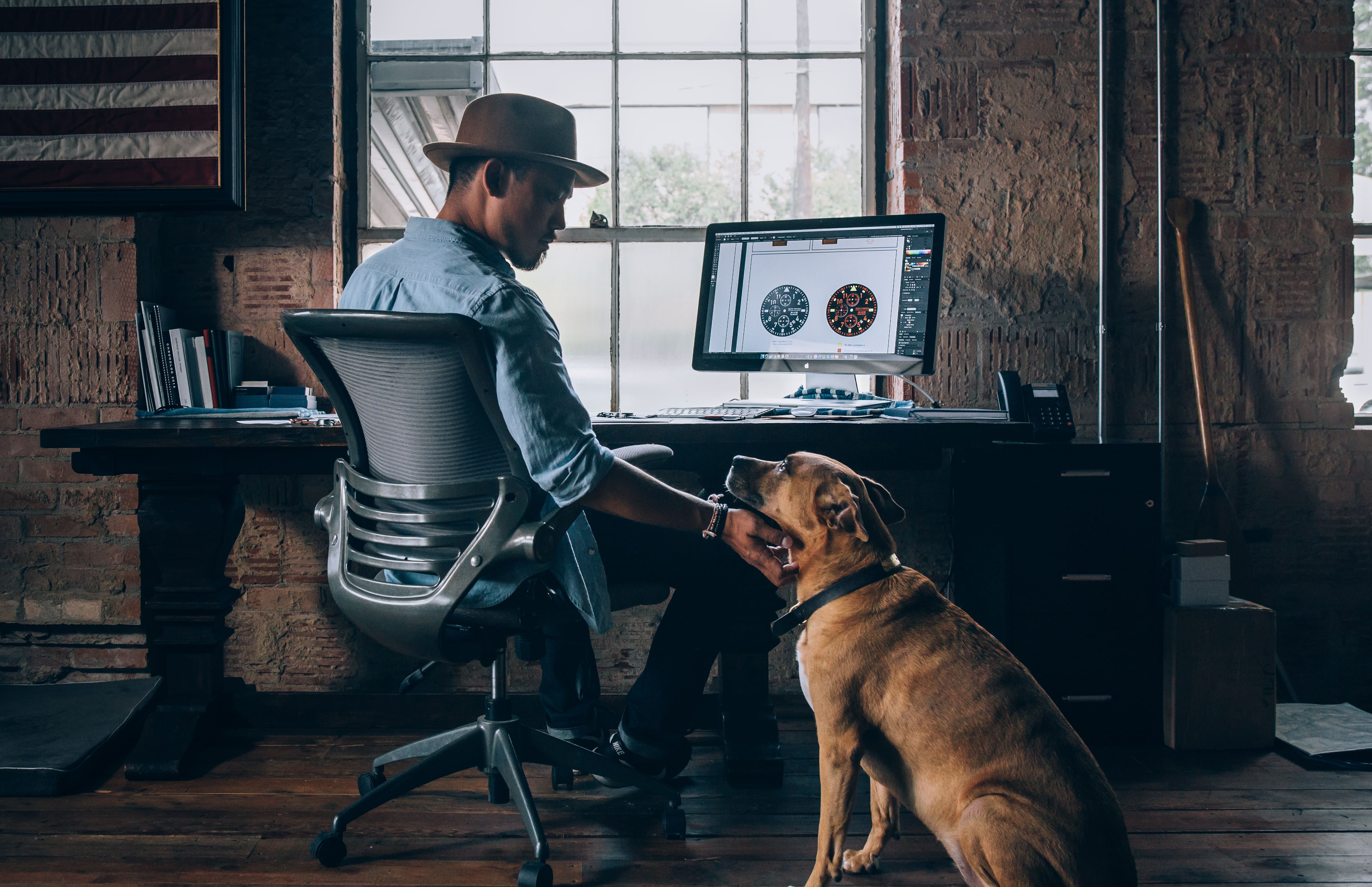 Homem fazendo carinho em seu cachorro enquanto trabalha home office